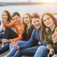 Summer holidays and teenage concept - group of smiling teenagers with skateboard hanging out outside.