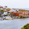 Charming Red and white cottages by the waterfront, with boats docked along the pier. Cold destinations travel trend. Kristiansand, Norway