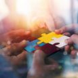 Business people join puzzle pieces in a modern office. Concept of teamwork and partnership. double exposure with light effects